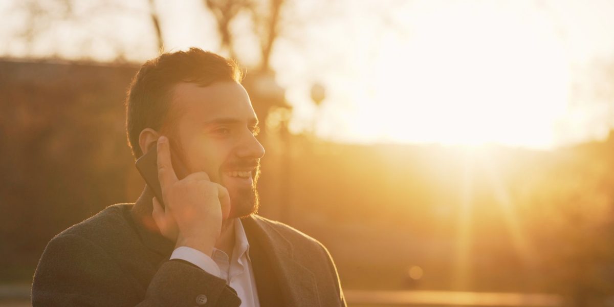 Persoană zâmbind în timpul unei discuții telefonice de afaceri