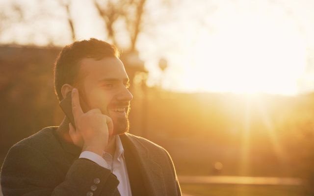 Persoană zâmbind în timpul unei discuții telefonice de afaceri
